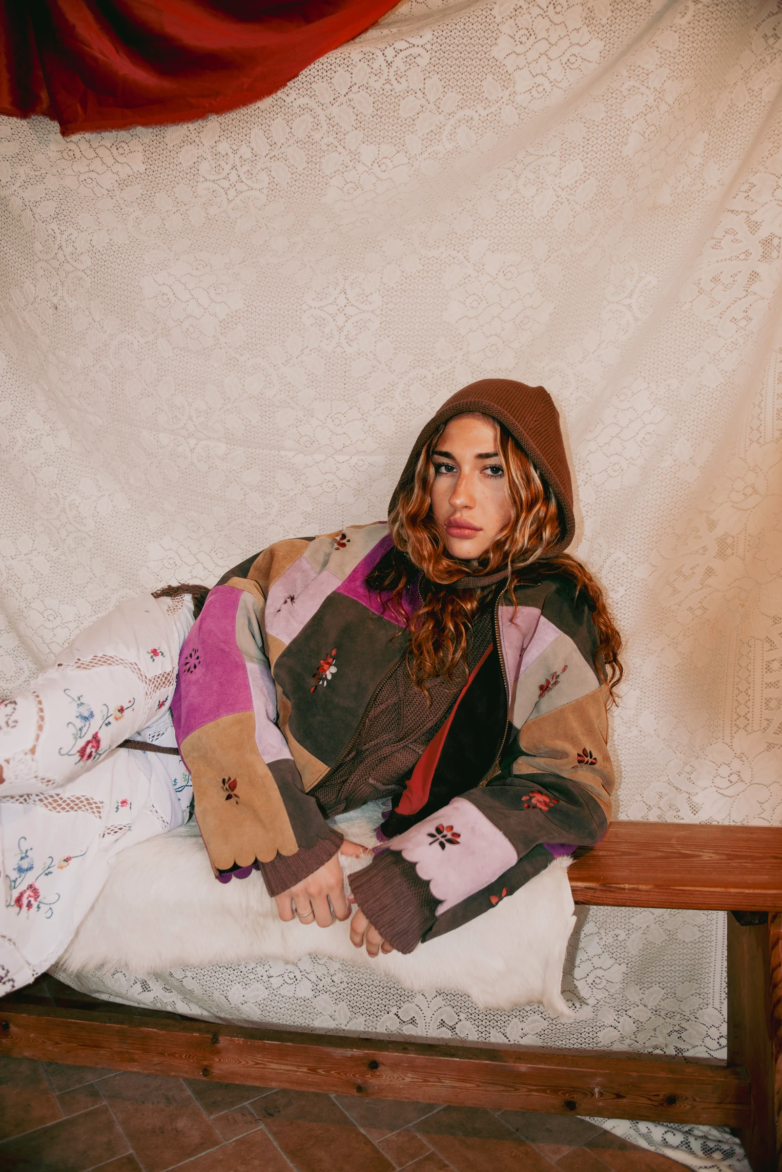 Look 1 — seated portrait showing floral cutwork and scalloped edges on the suede patchwork jacket