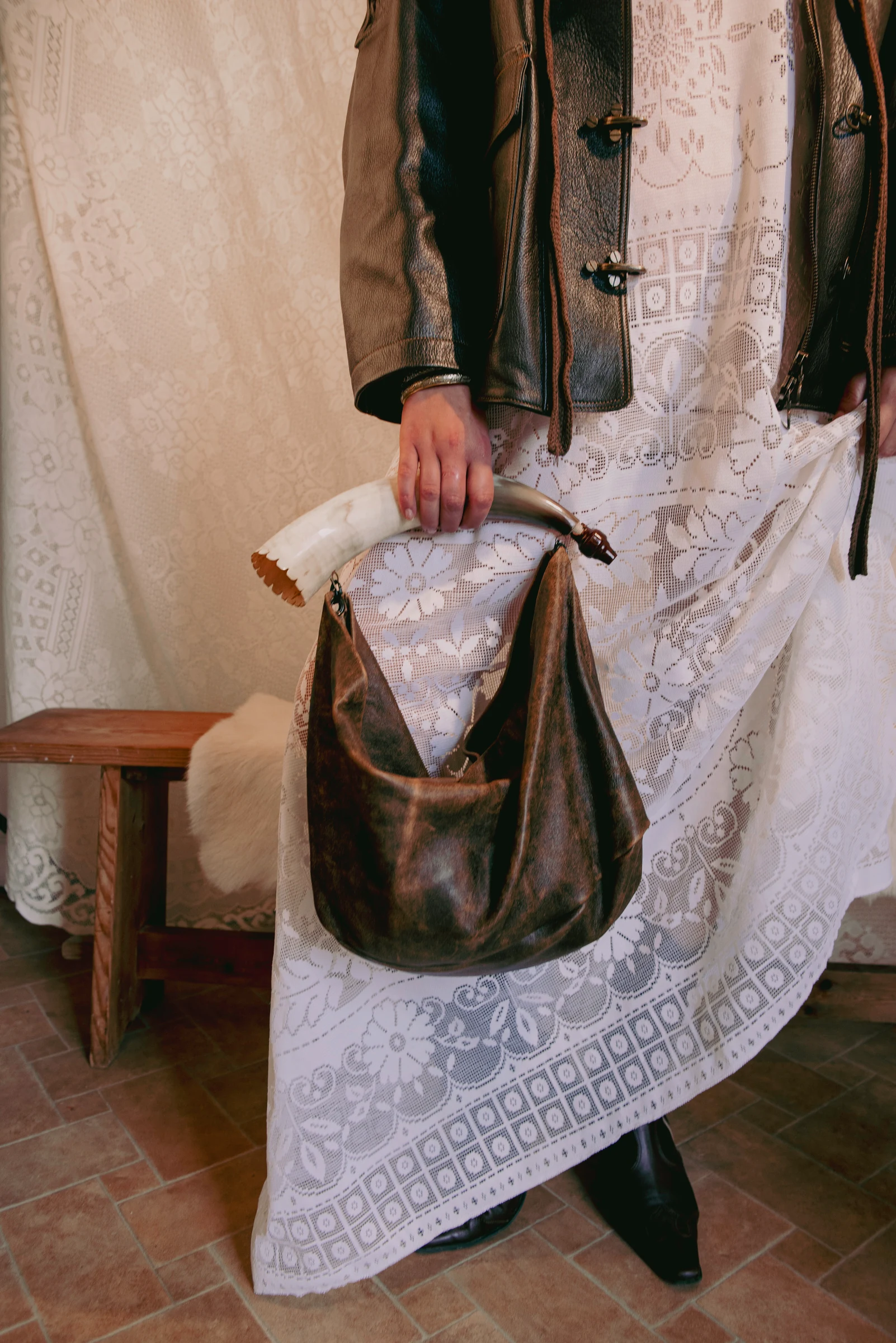 Look 2 — leather jacket and lace dress detail with a brown bag and curved bone handle