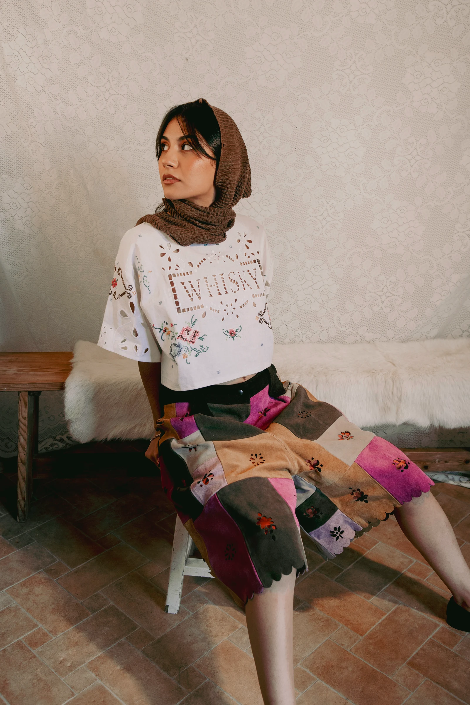 Look 3 — embroidered white cutwork top, multicoloured suede patchwork shorts and a brown knitted hood